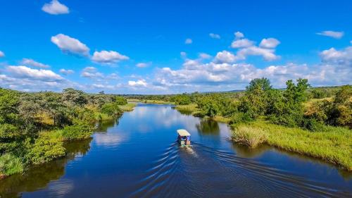 a small boat on a river in the middle at Royal Morubisi Founder's Lodge in Kaingo Private Game Reserve