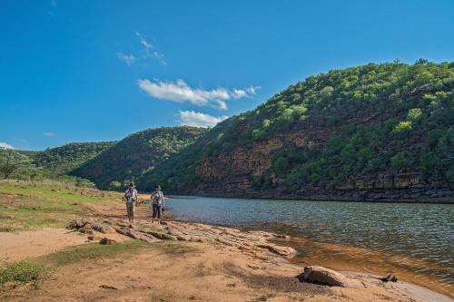 two people standing on the shore of a river at Royal Morubisi Founder's Lodge in Kaingo Private Game Reserve