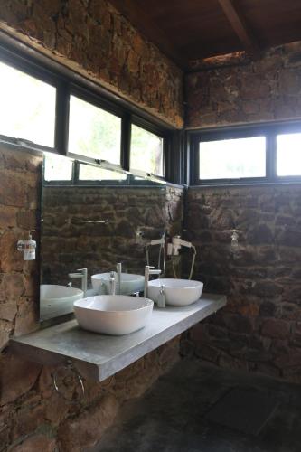 a stone bathroom with two sinks and a mirror at Passion Hills in Udawalawe