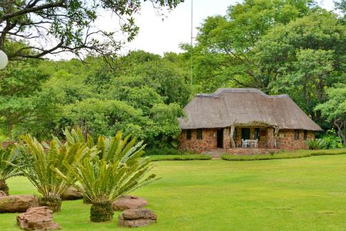 a stone house with a grass roof in a field at Royal Morubisi Founder's Lodge in Kaingo Private Game Reserve