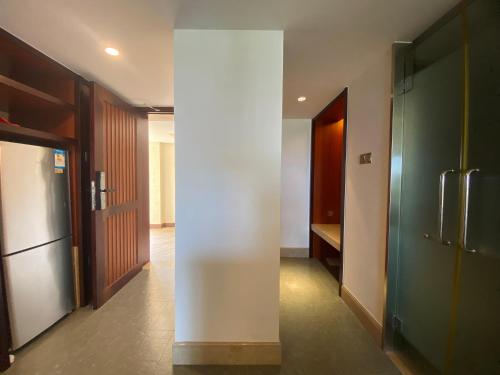 a hallway with a white wall and a refrigerator at Perfume Bay Tianhai Meiya B&B in Lingshui