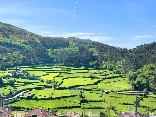 a view of a green field with mountains in the background at Refúgio Rural Ponte de Lima - Vista Verde e Tranquilidade in Ponte de Lima