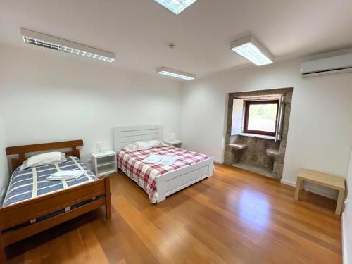 a bedroom with two beds and a wooden floor at Refúgio Rural Ponte de Lima - Vista Verde e Tranquilidade in Ponte de Lima