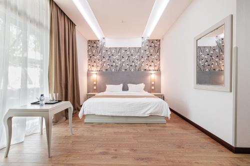 ein weißes Schlafzimmer mit einem Bett und einem Tisch in der Unterkunft Charos Family Resort in Yusufkhona