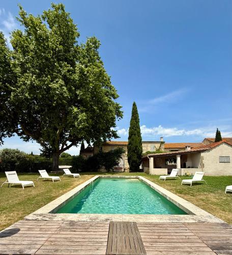 - une piscine dans une cour avec des chaises et un arbre dans l'établissement Le Mas des Flammes, à Arles