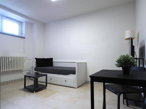 a white room with a bed and a table at Apartmán u Nové Karoliny in Slezská Ostrava