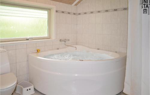 a white bath tub in a bathroom with a window at Holiday Home Fyrrelunden Oksbøl in Oksbøl
