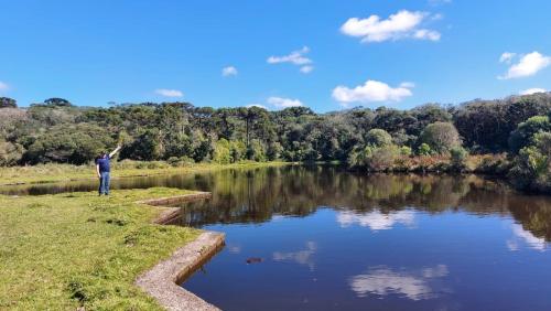 a man is standing next to a river at Rodeio das Lagoas Pousada in Cambara do Sul