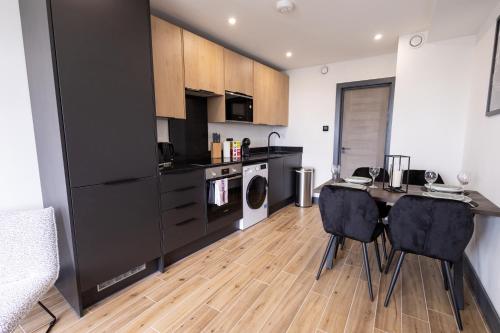 ボアハムウッドにあるBrand-New Top-Floor Flat with Stunning Balcony & Parkingのキッチン(黒いキャビネット、テーブル、椅子付)