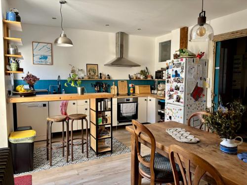 une cuisine avec une table et un réfrigérateur dans l'établissement Maison familiale en centre-ville, à Rochefort