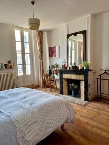 - une chambre avec un lit, une cheminée et un miroir dans l'établissement Maison familiale en centre-ville, à Rochefort