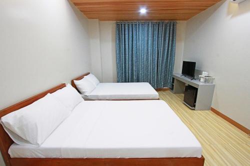 a hotel room with two beds and a television at Passage Point Guest House in Dauin