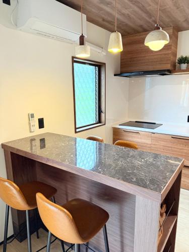 a kitchen with a counter with chairs around it at 興津ビーチサイドヴィラ 勝浦 - Okitsu Beachside Villa - Katsuura in Katsuura