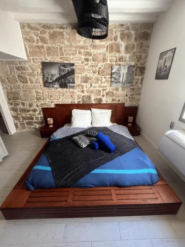 a bed in a room with a brick wall at Maison calme et climatisée - Proche Nîmes & Arles in Saint-Gilles