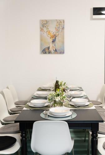 a long table with white chairs and a painting on the wall at Esprit Apartmanház in Szajol
