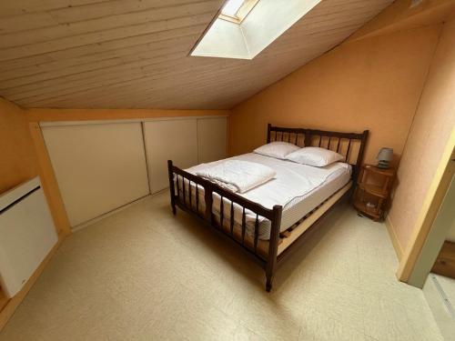 a bedroom with a wooden bed in a attic at Idéal famille - Proche sites touristiques in Moncoutant