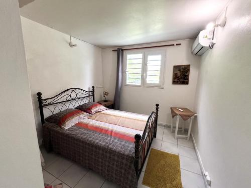 a small bedroom with a bed and a window at Villa plaisir de vivre in Petit-Bourg
