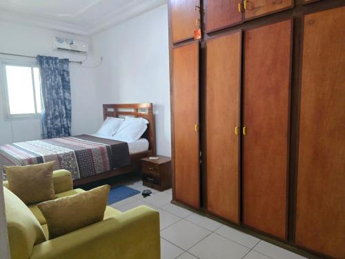 ein Schlafzimmer mit einem Bett, einem Stuhl und einem Schrank in der Unterkunft Douala séjour in Douala