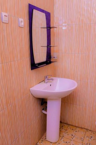a bathroom with a white sink and a mirror at Luna spa and Lodges in Kabuga