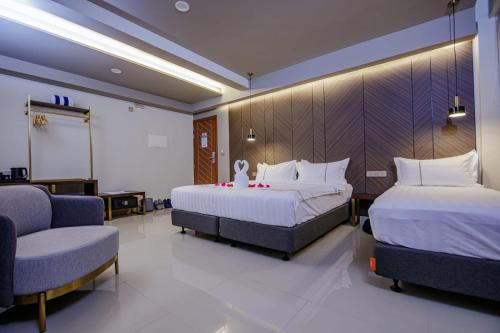 a hotel room with two beds and a chair at Royal Villa Fulidhoo in Fulidu