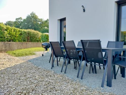 a dining table and chairs in a backyard at Maison contemporaine Plescop in Plescop