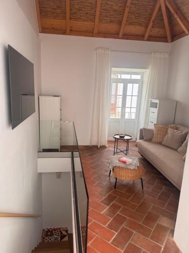 a living room with a couch and a table at Stylish townhouse with gallery in the heart of Tavira for two in Tavira