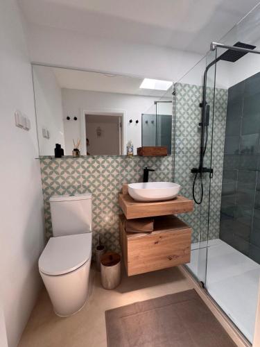 a bathroom with a toilet and a sink and a shower at Stylish townhouse with gallery in the heart of Tavira for two in Tavira
