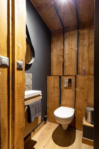 a bathroom with a toilet and a wooden wall at Villa - Détente & Jacuzzi aux portes de Gérardmer in Anould