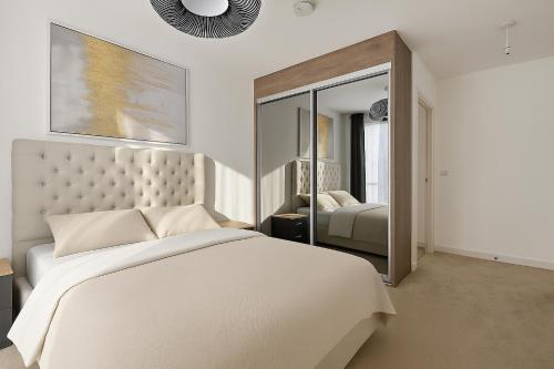 una camera da letto bianca con un letto e uno specchio di Mill Hill 2 Bed Apartment a Mill Hill
