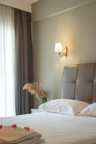 a bedroom with a white bed with a lamp and a window at Hotel Mironi and Victoria in Limenas
