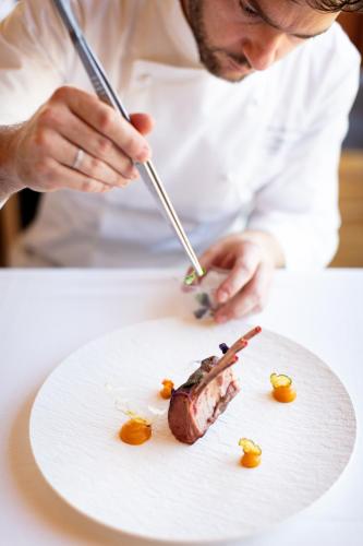 a man is cutting a piece of cake on a plate at Corona Dolomites Hotel in Andalo