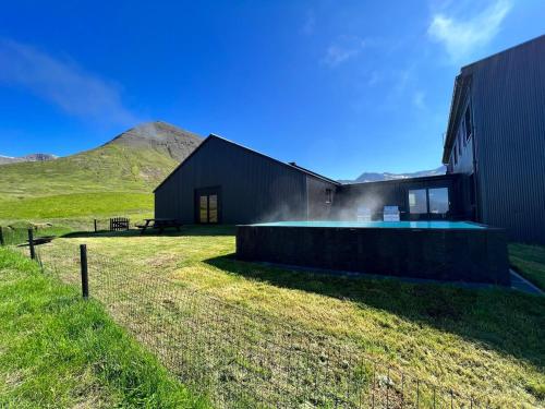 a black barn with a mountain in the background at Hóll Adventure House - Ævintýrahúsið Hóll á Siglufirði in Siglufjörður