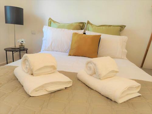 a white bed with two pillows on top of it at Caires Urban Nest in Braga