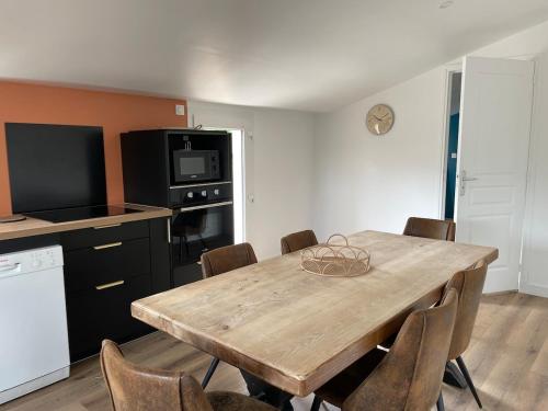 une cuisine avec une table en bois entourée de chaises. dans l'établissement Le Nid Familial, Maison cosy entre terre et mer, à Saint-Germain-de-Tournebut