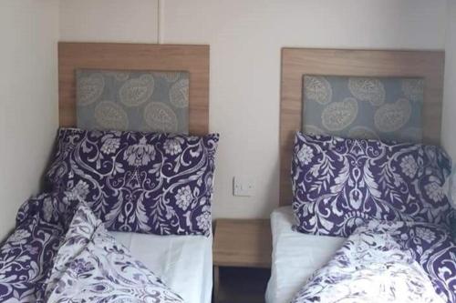 a bedroom with two beds with blue and white pillows at Purple Palace 3-Bed Caravan Ingoldmells in Ingoldmells