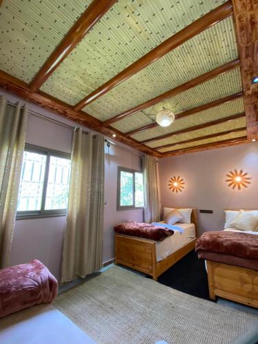 a bedroom with two beds and a wooden ceiling at Agafay Toubkal View in Imlil