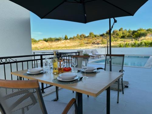 a wooden table with an umbrella on a balcony at Apartman Domnius in Škrip