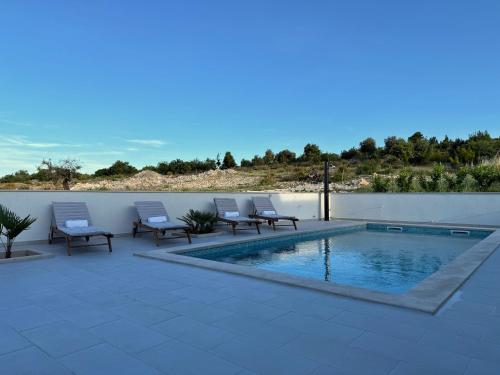 a swimming pool with lounge chairs next to a wall at Apartman Domnius in Škrip