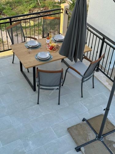 a wooden table and chairs with an umbrella on a balcony at Apartman Domnius in Škrip