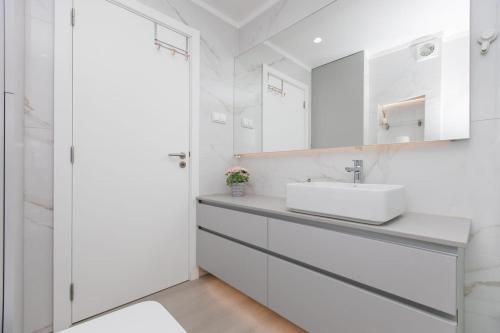 een witte badkamer met een wastafel en een spiegel bij Casa Nau - with pool and sea view in Sesimbra