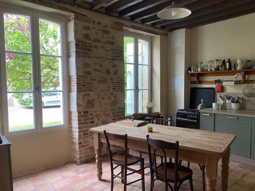 une cuisine avec une table et des chaises en bois dans l'établissement Les Roudons, à Saint-Sauveur-en-Puisaye