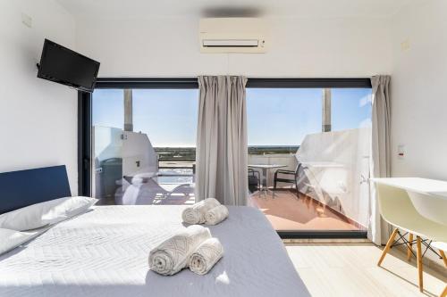 a bedroom with a bed and a large window at Cabanas de Tavira - Studio in Cabanas de Tavira