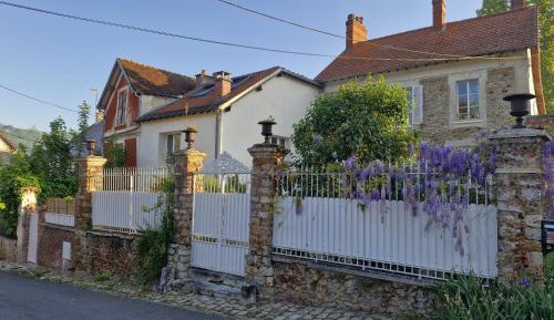 a white fence in front of a house with purple flowers at A la LampePigeon, un gîte avec jardin et du calme, 3 min de la Ferté-sous-Jouarre, 42 min de Paris TER, 35 min de Disney, 10 min de l'A4 in Reuil-en-Brie