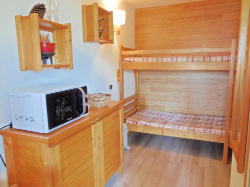 Cette chambre comprend 2 lits superposés et un four micro-ondes sur un comptoir. dans l'établissement Studio divisible 4 pers. - Balcon, Animaux admis, Pied des pistes, Proches commerces - FR-1-353-74, à La Plagne
