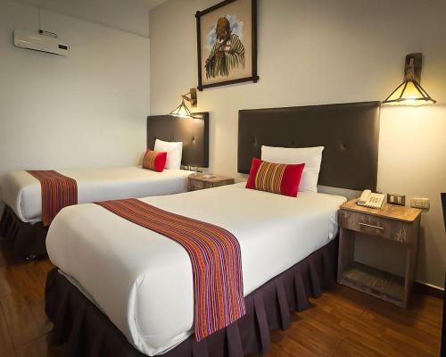 a hotel room with two beds and a telephone at Hotel Monasterio San Pedro in Cusco