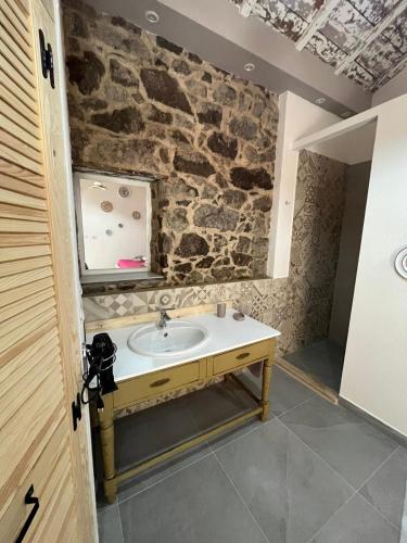 a bathroom with a sink and a stone wall at B&B Salaju in Castelsardo