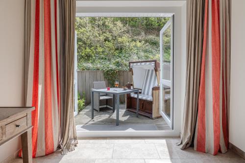 an open door to a patio with a table at Apartmenthotel am Leuchtturm in Hörnum