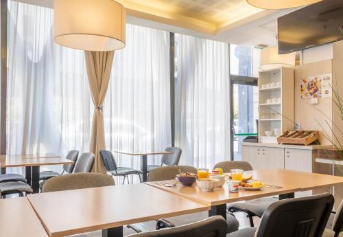 une salle à manger avec tables, chaises et fenêtres dans l'établissement B&B HOTEL Marseille Centre La Timone, à Marseille