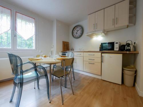 une cuisine avec une table et des chaises et une horloge au mur dans l'établissement Le nid de la Canopée, à Montpellier