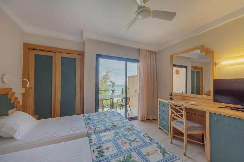 a bedroom with a bed and a desk with a television at PortBlue Club Pollentia Resort & Spa in Alcudia